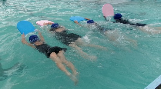 ビート板を使って水に浮く練習をする児童たちの写真