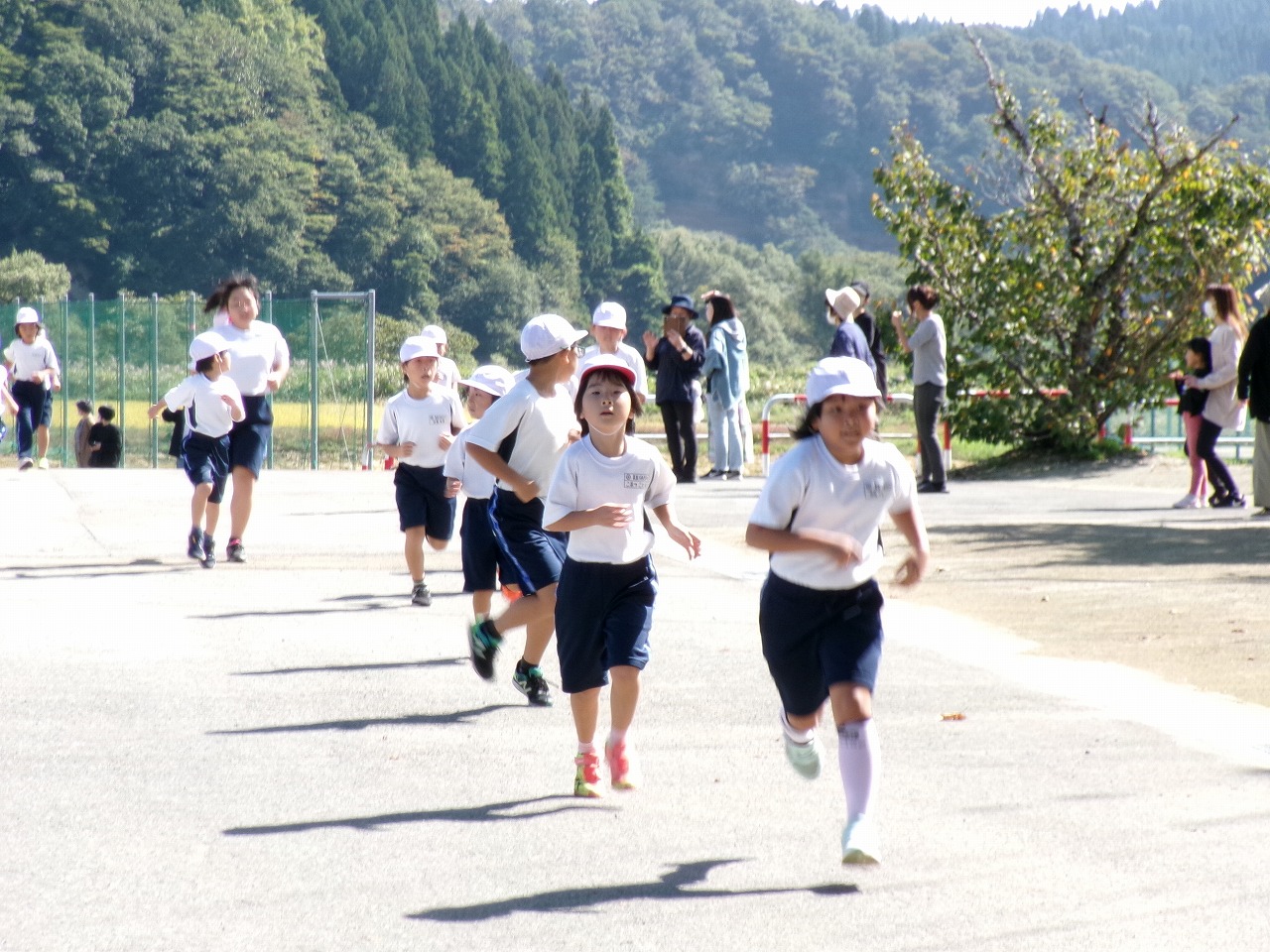 学校の敷地外に出て懸命に走る低学年の児童たちの写真