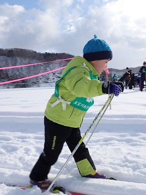 雪原をスキーで走る小柄な児童の写真