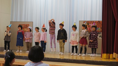 きらびやかなとんがり帽子を被って小さなくつやさんを演じる1年生児童の写真