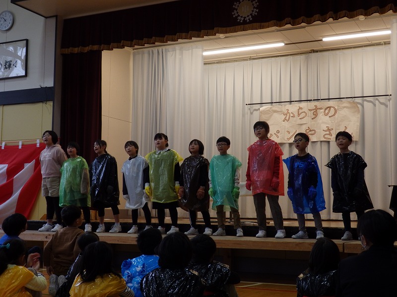色とりどりのビニール袋を使った衣装を身につけ「からすのパンやさん」を演じる3年生の児童たちの写真