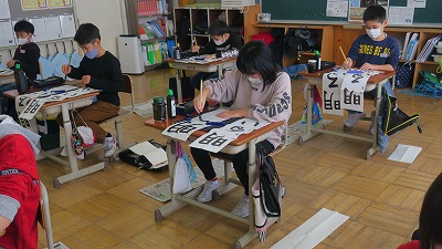 書き初めをする4年生の生徒たちの写真