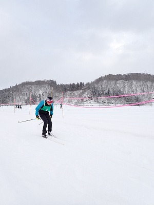 雪原に小さく見える青いスキーウェアの児童の遠方からの写真