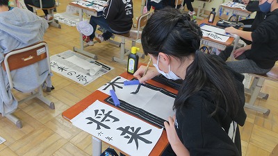 「将来」という言葉を書き初めする6年生の生徒たちの写真
