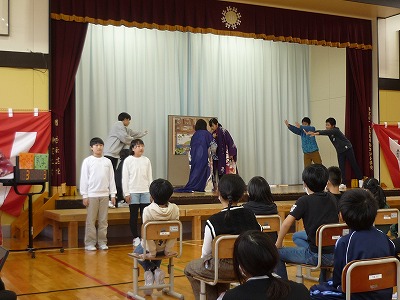舞台上や舞台下をいっぱいに使ってタピオカ・ツンドラの劇を演じる6年生児童たちの写真