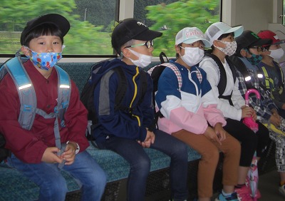 校外学習にて、電車内のシートに姿勢良く座る、2年生の児童6人の様子を写した写真