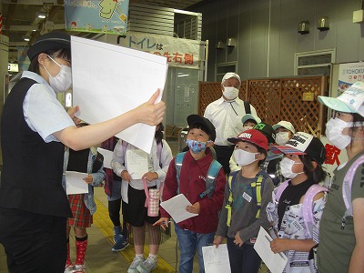 校外学習にて、新庄駅の女性駅員から、新幹線「つばさ」についての説明を聞く2年生の児童達の様子を写した写真