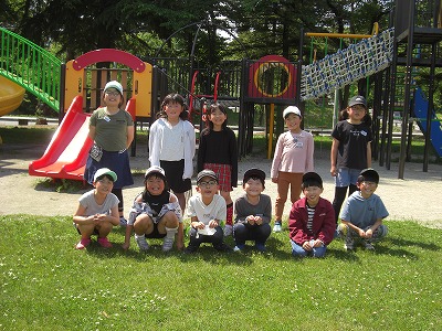 校外学習にて、新庄市内の公園で、公園の遊具を背景に2列に並んで撮影された、2年生の児童11人の記念写真