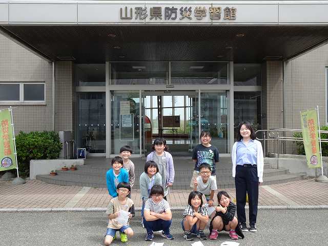 山形県防災学習館の入口前で撮影した笑顔の児童たちの集合写真