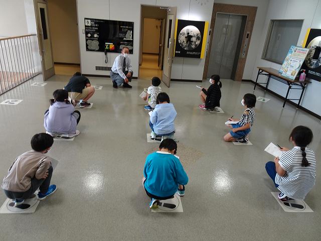火災の避難時の行動を説明している職員の説明を真剣に聴いている児童たちの写真