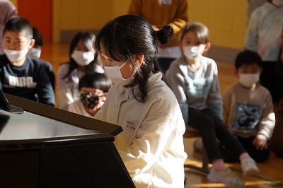 ピアノの演奏を披露する白いトレーナーを着た女子児童の写真