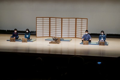 障子の衝立の前に正座する4人の昔語りクラブの児童たちの写真