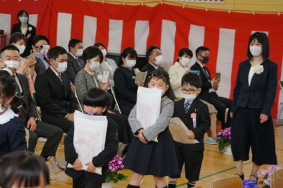 教科書を両手で抱えながら退場する新入生たちの写真