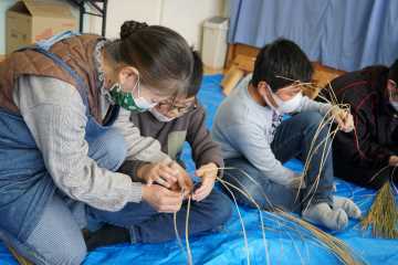 縄の綯い方を児童に教える「平枝炭焼き保存会」の女性の写真