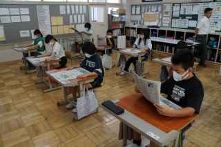 自分の席でそれぞれ新聞を開いて一生懸命に読んでいる児童たちの写真