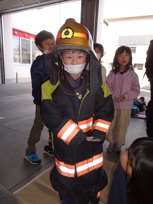 消防服を着ている男の子とそれを見ている子供たちの写真