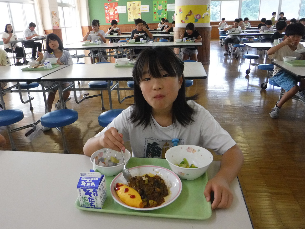 給食を食べながらカメラ目線でにっこりしている子供の写真