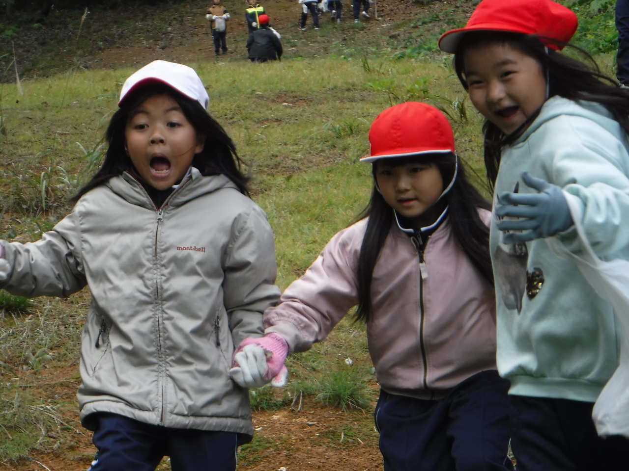 手をつなぎあいながら歩く三人の子供の写真
