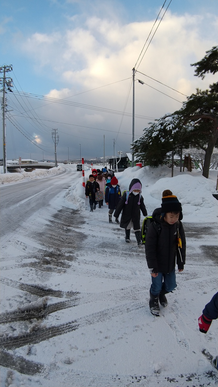 雪の積もった道を並んで歩く子供たちの写真
