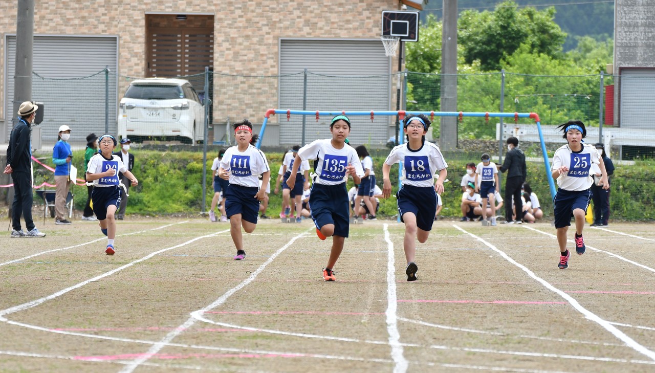 鉢巻を巻いた体操服姿の5人の男女がまっすぐ走ってきている写真
