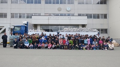 小学校校舎前で活動に参加した子供たちと地域の皆さんで撮影した集合写真