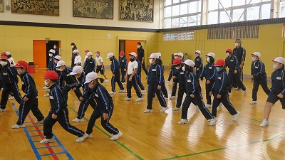 体育館で外部講師の指導の下ダンスを練習する児童たちと先生の写真