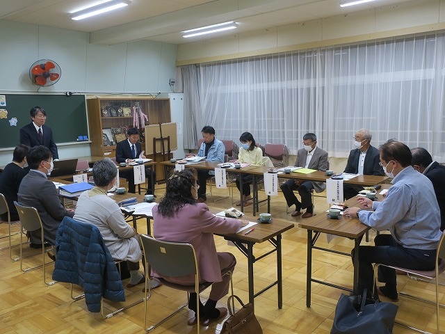 教室でロの字型に机を並べ、男女合計12人の参加者が学校運営協議会で意見交換している様子の写真