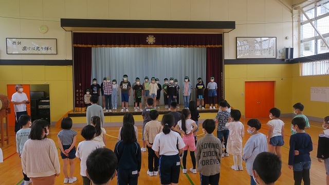 学校の体育館の壮行式の前で立って話す生徒たちと立って聞く生徒たちの写真