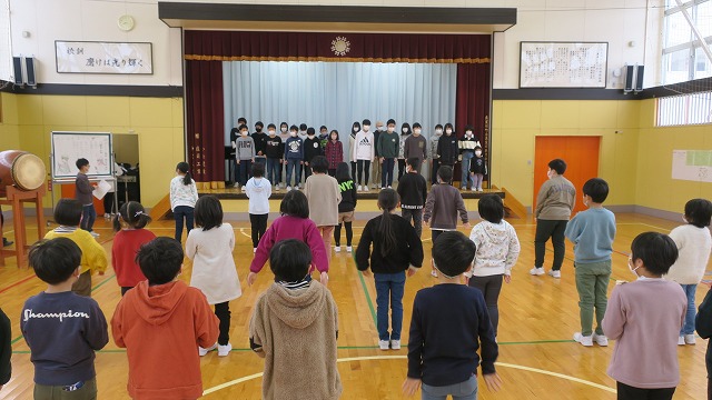 ステージ上で今回の目標を語る5・6年生と、ステージの下でそれを聴いている1～4年生の写真