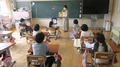 子どもたちに絵を見せながら読み聞かせをしている女性の写真