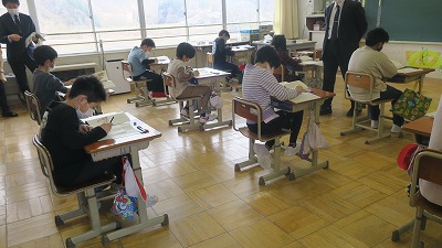 机に向かって授業のノートをとる児童たちの写真