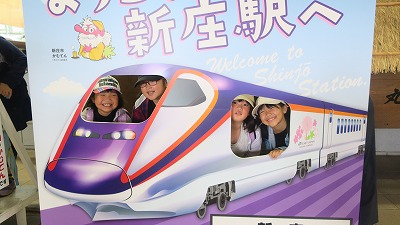 校外学習にて、JR新庄駅で、「ようこそ新庄駅へ」と書かれ、新幹線の絵が描かれた顔出しパネルで遊ぶ、2年生の女子児童4人の様子を写した写真