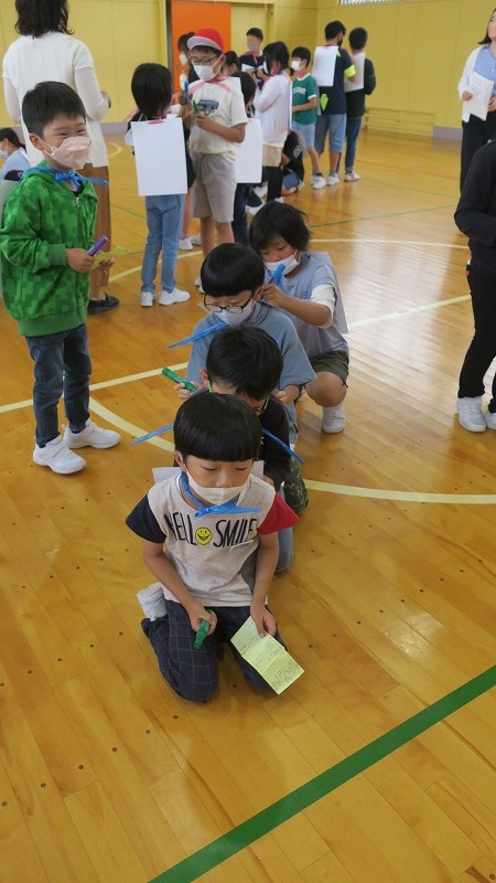 背中に貼った画用紙に、運動会での頑張りについてお互いに書き合いっこをする児童たちの写真