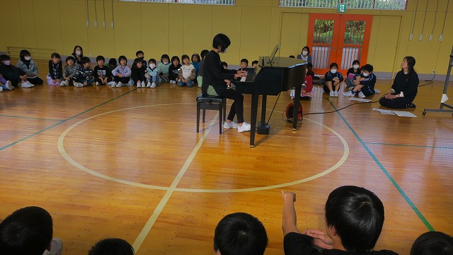 先生のピアノ演奏に聞き入っている生徒たちの写真