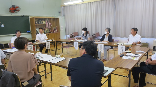 教室でテーブルをロの字型に並べ9人の参加者が会議をしている様子の写真