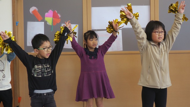 ピカピカの飾りが付いた手を大きく広げ決めポーズする生徒たちの写真