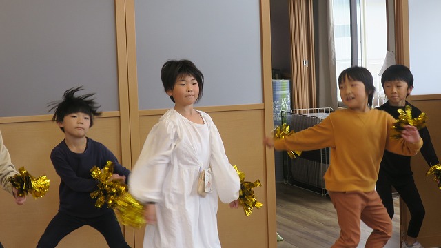 ピカピカの飾りを激しく動かしダンスする生徒たちの写真
