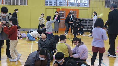 児童たちと保護者の皆さんが、体育館の床で一緒に作業している写真