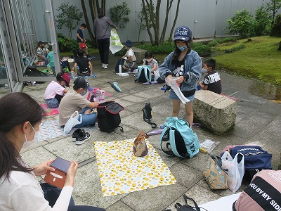 交流センターの石畳の中庭にシートを敷いて昼食をとる児童たちの写真