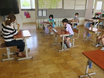 着席したサークルの女性が、こちらも着席した3年生の児童たちに読み聞かせをしている写真