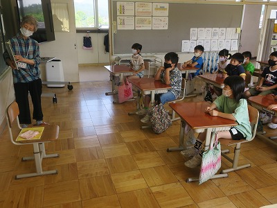 サークルの女性が、着席した2年生の児童らに読み聞かせをしている写真