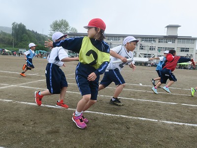 バトンを持って走りだそうとする男子児童と、バトンを受け取ろうとする女子児童の写真