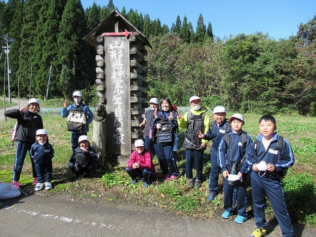 「神室少年自然の家」の立て看板の前で、思い思いのポーズをとる児童たちの写真