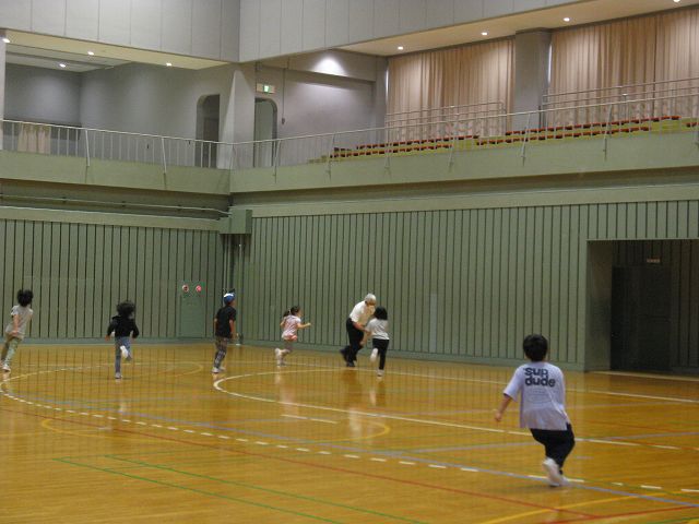 体育館の広い競技場を元気に走り回る児童たちの写真