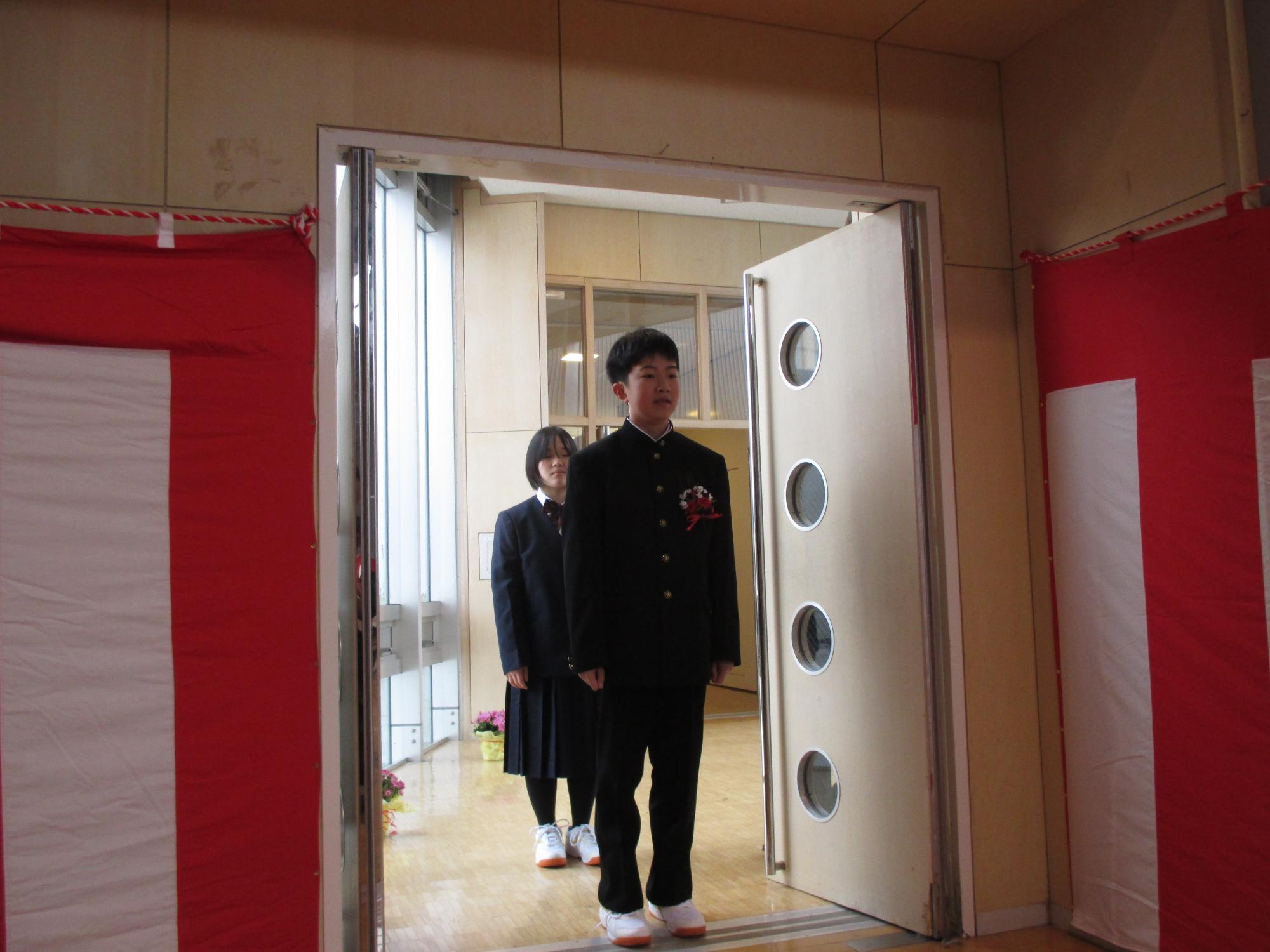 体育館に入場する、詰襟の制服を着た卒業生の写真
