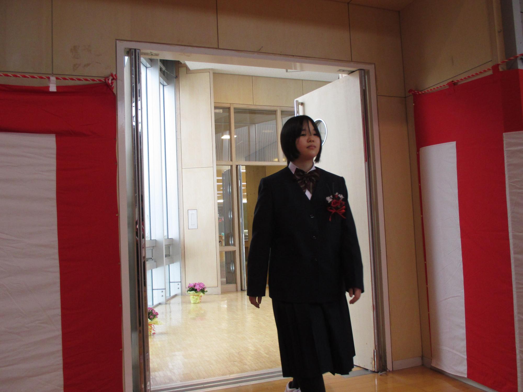 体育館に入場する、ブレザーの制服を着た女子卒業生の写真