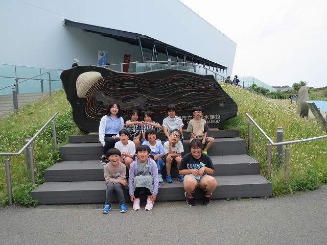 大きなクラゲが描かれた看板の前で記念撮影をする児童たちの写真