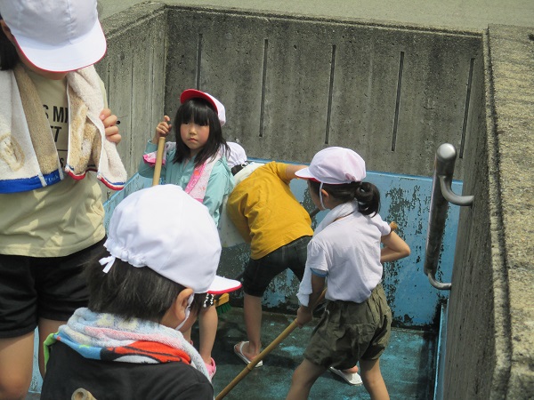 子供たちがプールの床磨きをしている写真
