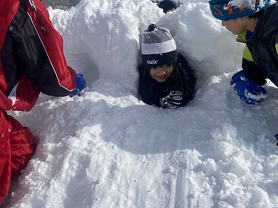 雪に穴掘りをする生徒たちの写真