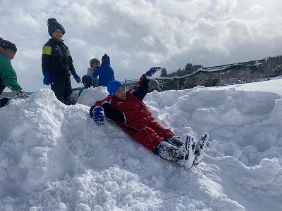 雪の滑り台で遊ぶ生徒たちの写真